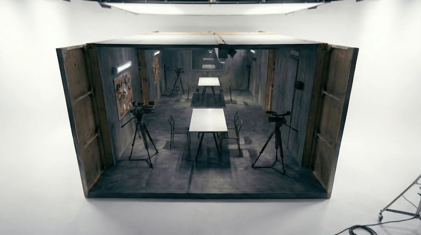 Salle d'interrogatoire d'Alibi vue en plongée, deux tables blanches alignées
