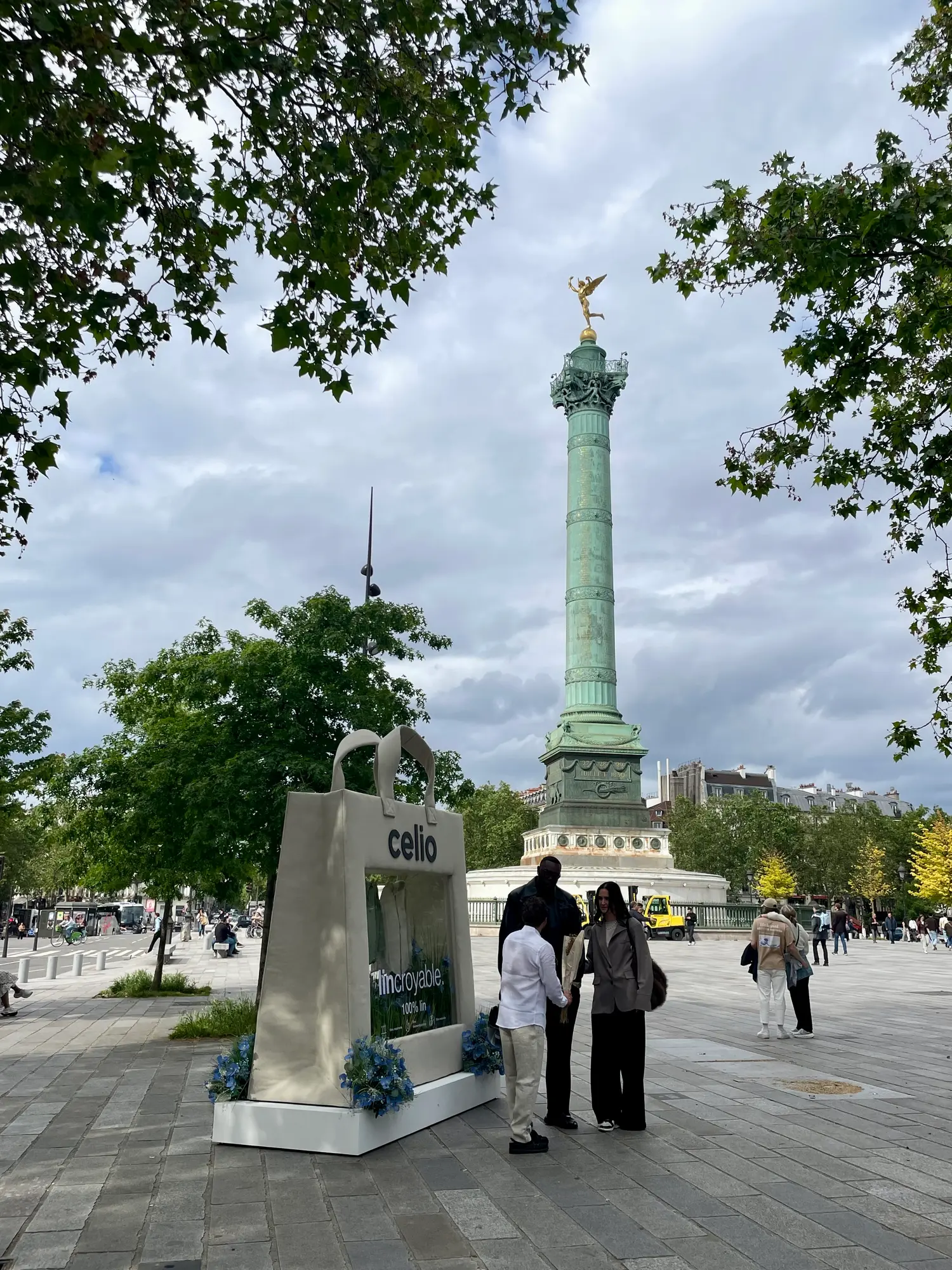 Le sac géant Celio au pied de la colonne de Juillet, place de la Bastille, avec des passants devant